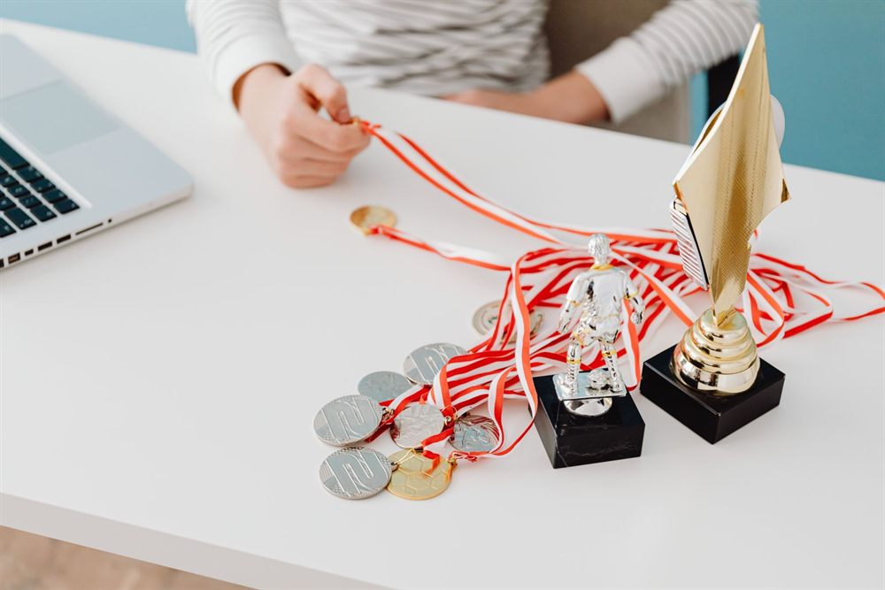 Trophies and ribboned medals on a desk beside a laptop