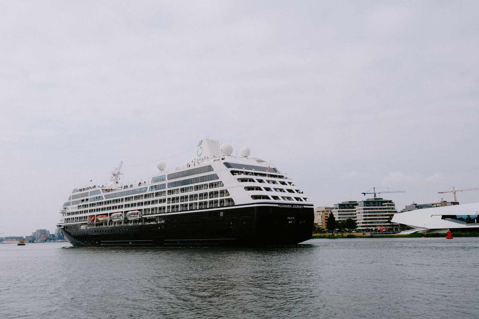 Mid-size cruise ship at anchor off a city waterfront