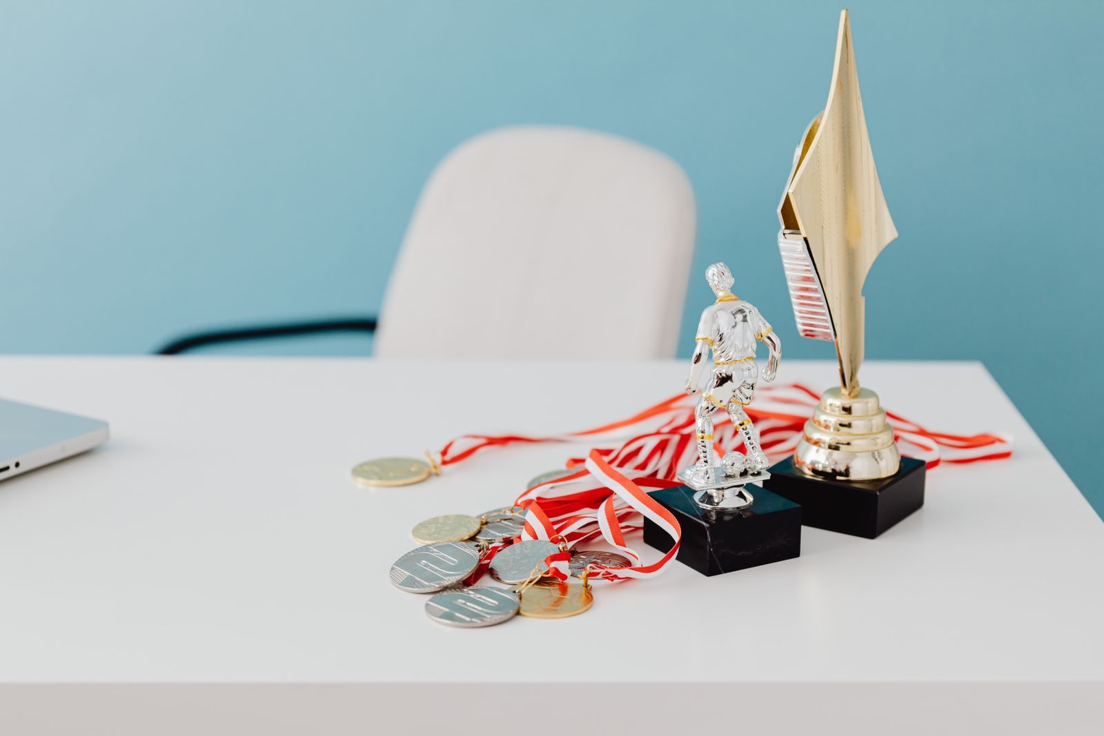Gold trophies and ribboned medals on a white table